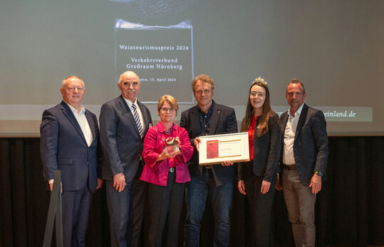 bergabe der Urkunde des Weintourismuspreises 2024 (v. l.): Vorsitzender Tourismusverband Franken Thomas Bold, Prsident Frnkischer Weinbauverband Artur Steinmann, VGN-Geschftsfhrerin Anja Steidl, VGN Referent Freizeit und Stdtetourismus Ulrich Bscher, 66. Frnkische Weinknigin Lisa Lehritter und Staatsminister Thorsten Glauber.