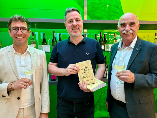 Marco Maiberger vom Frnkischen Weinland (links) und Weinbauprsident Artur Steinmann (rechts) beglckwnschten Johannes Quirin zu seinem gelungenen Reisefhrer. 