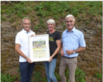Volker Ahnen, Bürgermeister von Senheim und Stefanie Vornhecke präsentieren mit Norbert Müller, Dienststellenleiter DLR Mosel (v.l.), die Urkunde zum neuen Leuchtpunkt der Artenvielfalt.