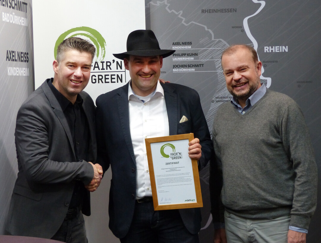 Dr. Keith Ulrich (r.), Vorstandsvorsitzender FAIR’N GREEN, und Philipp Kuhn (l.), FAIR’N GREEN Partnerwinzer aus der Pfalz, überreichten Martin Steinmann (Mitte) das FAIR’N GREEN-Zertifikat.