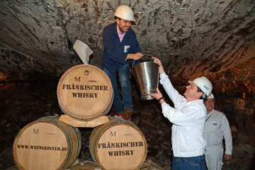 Martin Mlein (l.), frnkischer Winzer und Whiskybrenner, und Thorsten Boeckers (r.), Finanzvorstand der K+S Aktiengesellschaft, befllen das Whiskyfass in 600 Meter Tiefe. 